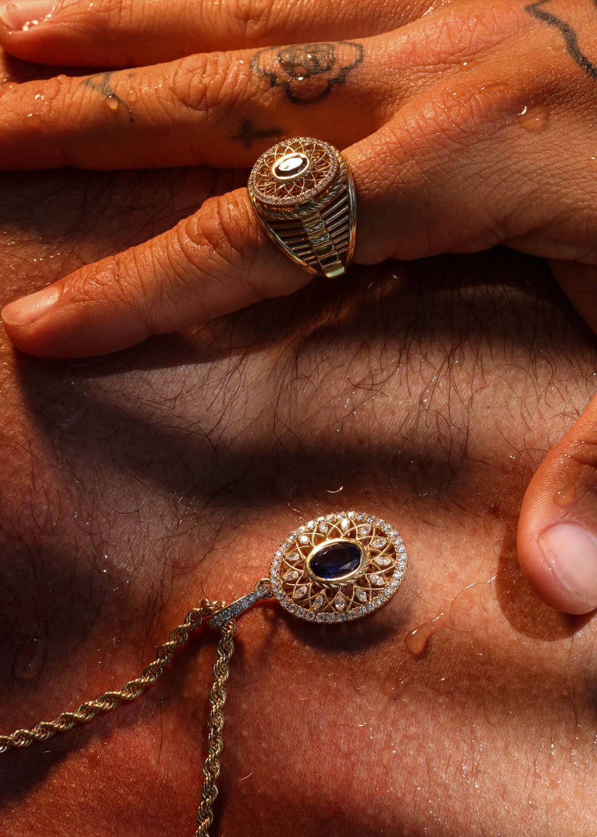 Close-up of a hand with gold rings and a necklace on a textured surface