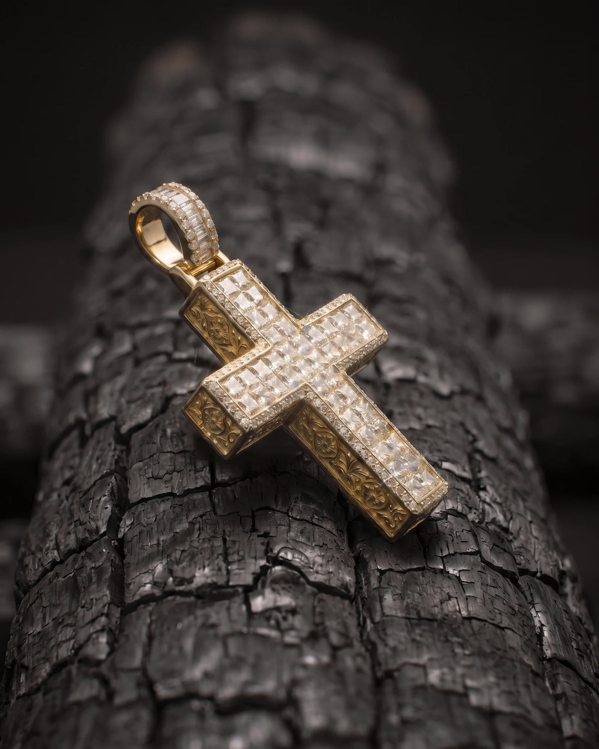 The Sanctum Cross three-quarter view on a charred log, showing the pave bevel and engraved side walls